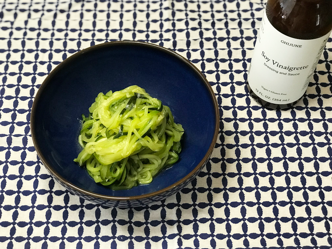 A bowl of zoodle with a bottle of condiment