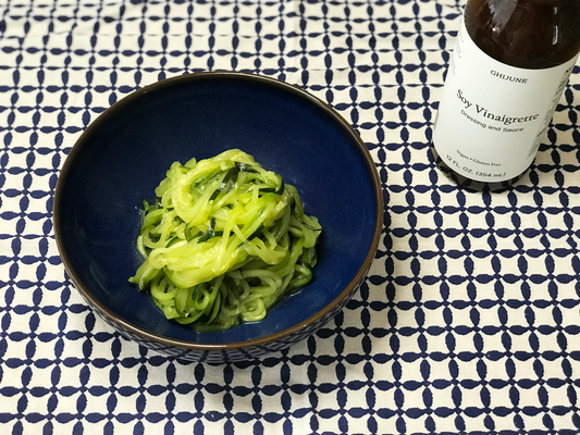 A bowl of zoodle with a bottle of condiment