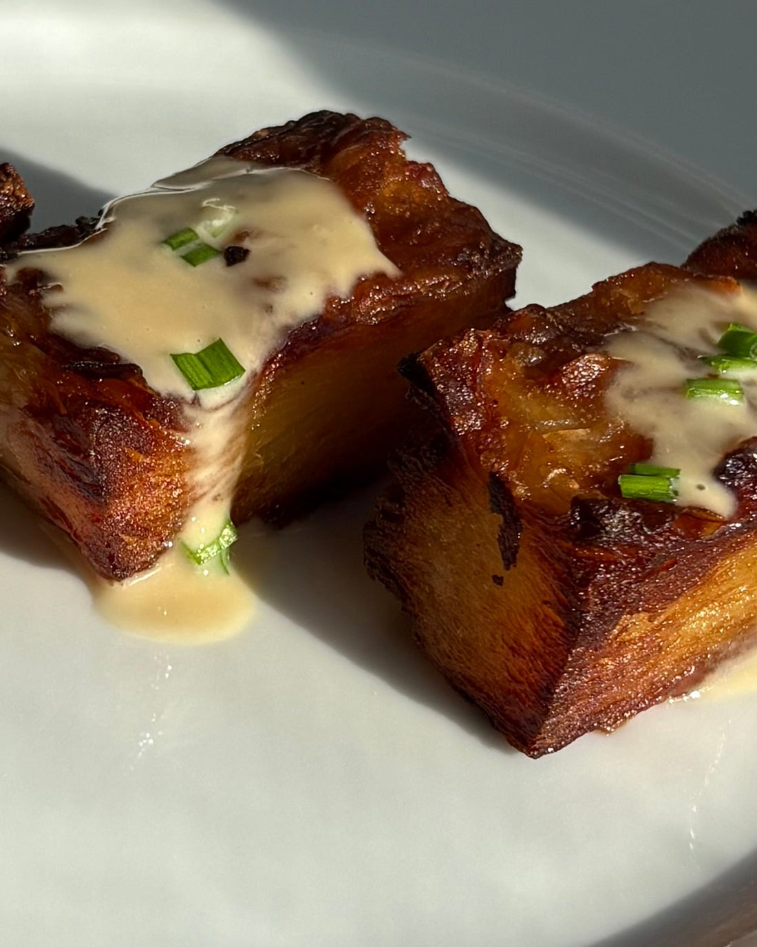 Golden, crispy thousand layer potatoes stacked and served with a creamy GHIJUNE and crème fraîche dipping sauce, garnished with fresh herbs for a rich and elegant presentation.