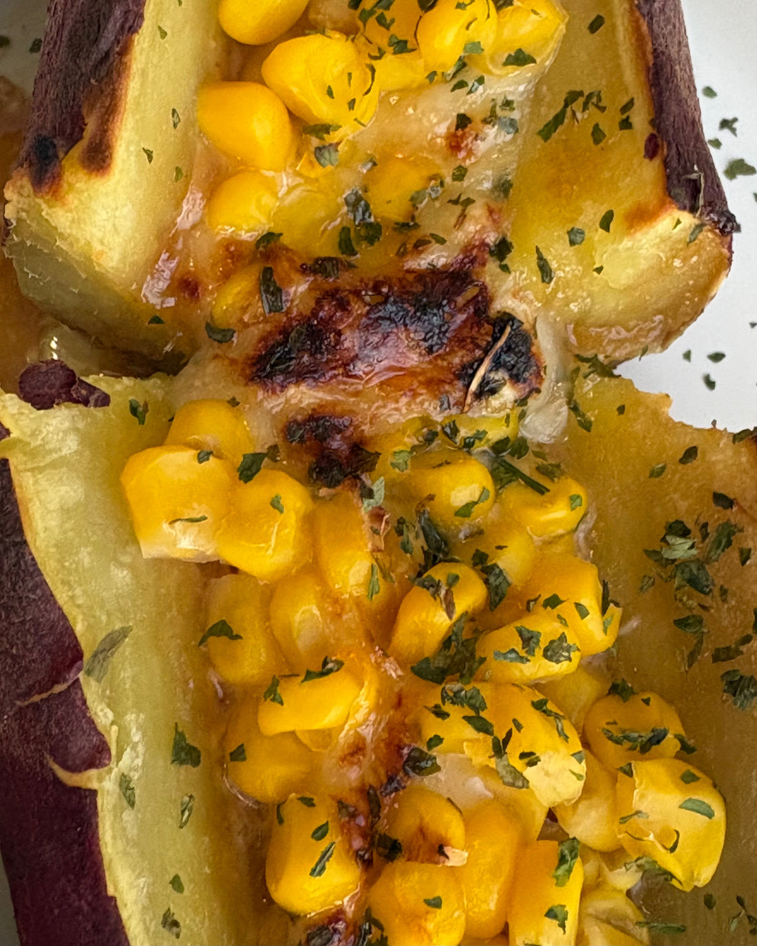 Baked sweet potato split open and topped with melted butter, gooey cheese, sweet corn, pastel, and a drizzle of GHIJUNE Soy Vinaigrette, broiled until golden and served hot.